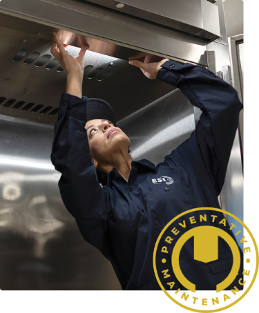 ESI technician reaching up under a stainless steel commercial oven, overlaid with a gold Preventative Maintenance badge