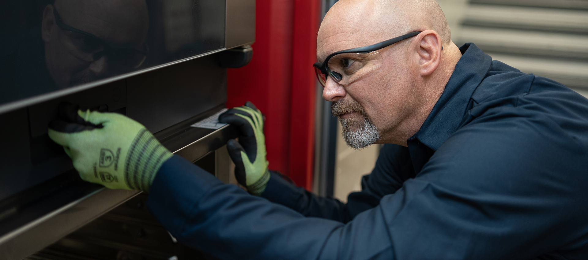 ESI technician in safety glasses and cut-resistant gloves opening the door of a commercial oven